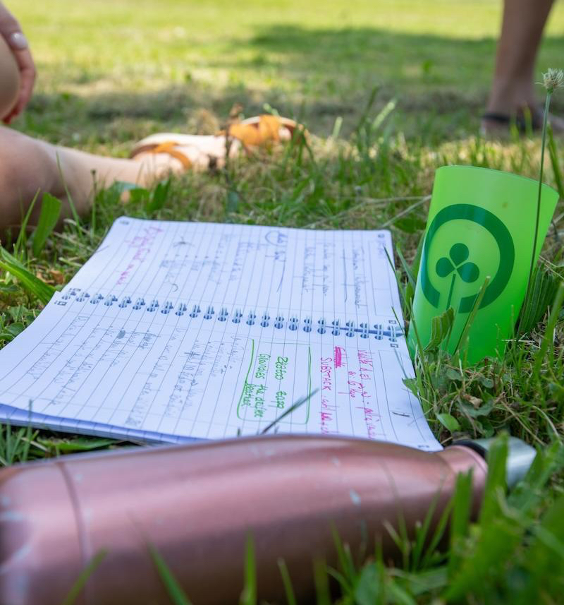 un carnet, une gourde et un verre sur l'herbe